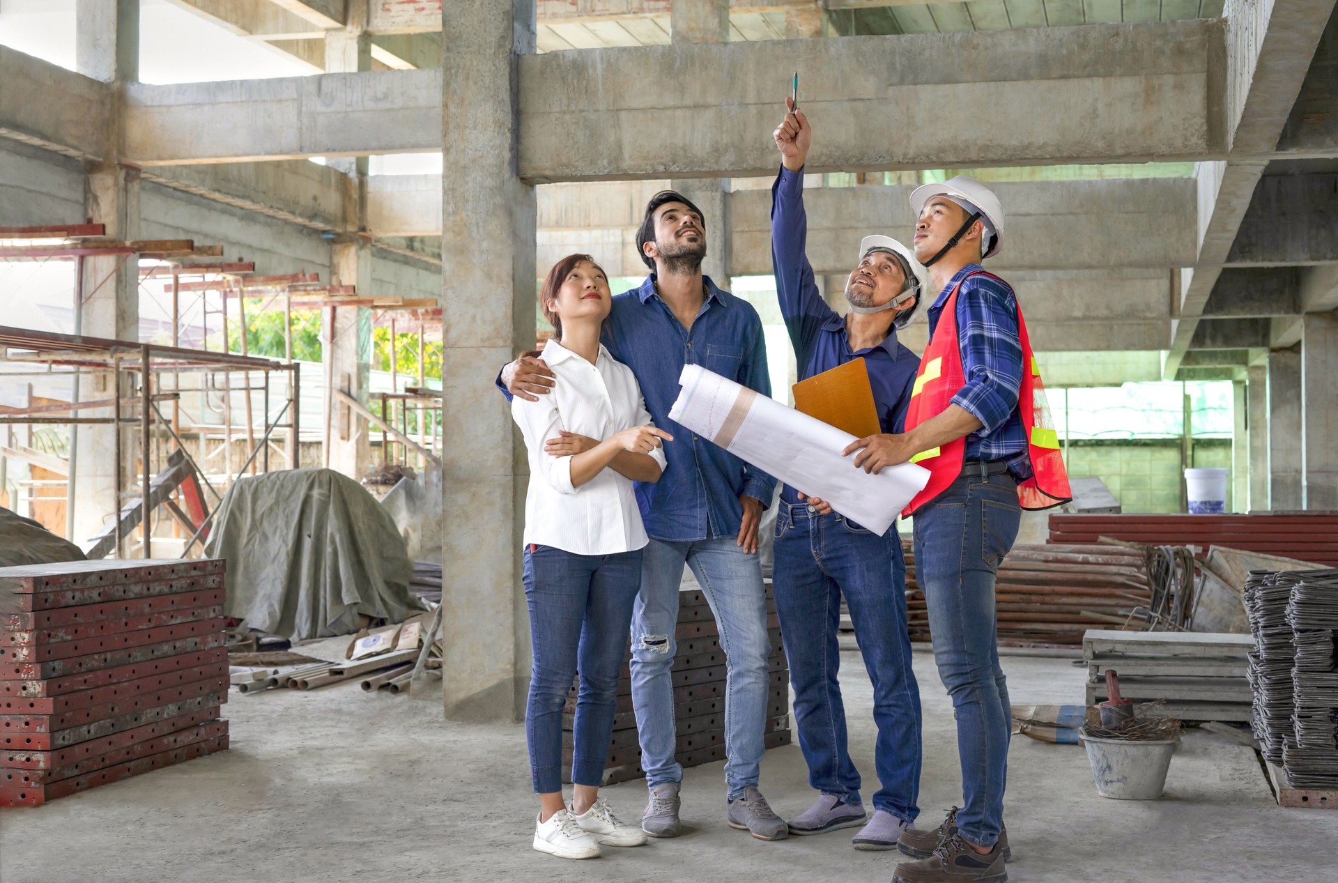 happy family visiting and talking to contractor at site,engineer or architect explain progress of a house building with construction paper to young couple